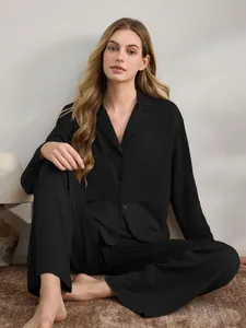 Elegante Frau in einem schwarzen langärmeligen Schlafanzug-Set auf weichem Boden