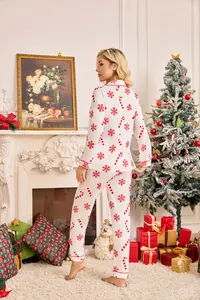 Back view of woman in white Christmas pajamas with red snowflakes in festive room.
