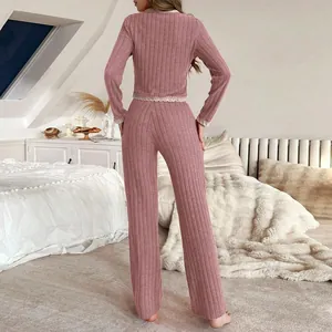 Conjunto de pijama de dos piezas rosa con encaje blanco y pantalones largos ajustados.