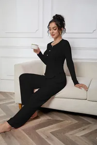 Close-up of black ribbed long-sleeve loungewear set on a model sitting on a sofa