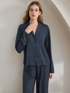 Frau trägt ein weiches, kohlegraues, langärmeliges Pyjama-Set mit Knopfleiste zu Hause