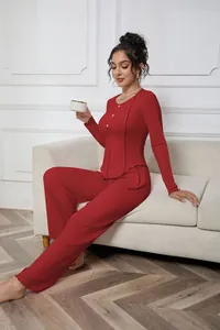 Model wearing a red ribbed long sleeve top and pants pajama set on a white sofa