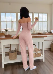 Back view of a woman wearing a pink off-the-shoulder loungewear set in a bright kitchen