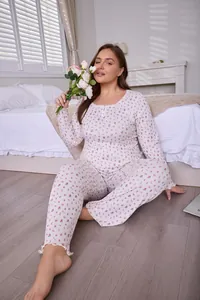 Full view of plus size women's floral pajama set with long sleeves and pants in a bedroom