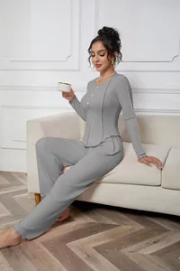 Elegant women's grey ribbed long-sleeve pajama set shown in a cozy home lounge setting.