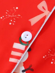 Détail macro du tissu de pyjama de Noël rouge pour femmes avec bouton blanc et motif festif