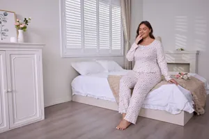 Women's plus size floral pajamas set with long sleeves in a cozy bedroom setting
