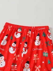 Détail d'un pantalon de pyjama de Noël rouge avec motifs de bonhommes de neige festifs.