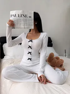 Cozy white ribbed knit pajama set with black bow details on bed