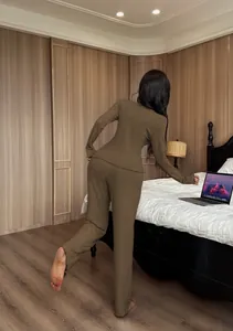Back view of a woman wearing a dark olive ribbed knit pajama set in a bedroom setting