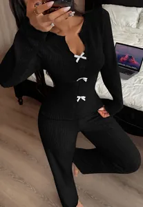 Close-up of black ribbed knit lounge set featuring white bow details