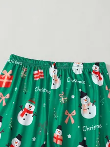 Vue détaillée d'un pantalon de pyjama de Noël vert avec des motifs de bonhomme de neige et cadeaux.