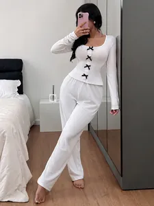 Detail view of cozy white ribbed knit pajama set with black bow accents on a model