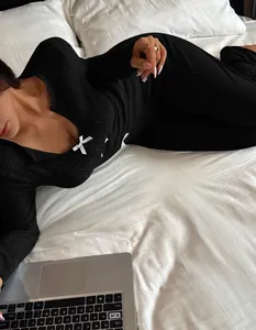Macro detail of black V-neck knitted loungewear set featuring white bow accents.
