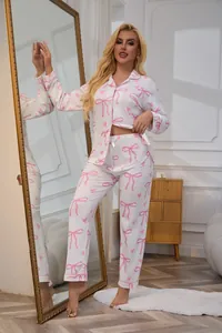 Detailed view of women's white pajama set with pink bow prints in a home setting