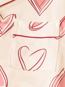 Detail shot of the pink heart pattern and chest pocket on a soft satin pajama top