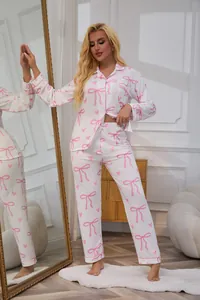 Full view of women's white pajama set featuring pink bow and heart prints in a cozy room