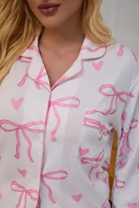 Close-up detail of women's white pajama top with pink bow and heart print patterns.
