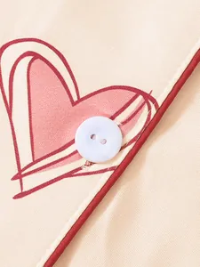 Close-up of heart print pajama detail with white button and red piping trim