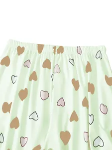 Close-up view showing the elastic waistband of light green pajama pants with heart print