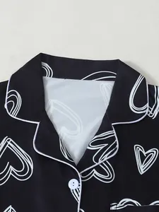 Close-up detail of a black heart print pajama top featuring white piping and a lapel