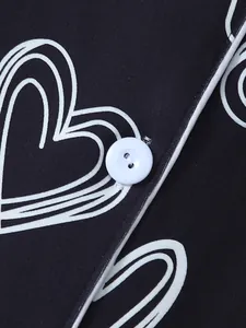 Macro view of heart print fabric and white button on soft black loungewear set