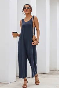 Detail view of a navy blue sleeveless wide-leg jumpsuit worn by a model in a urban setting.