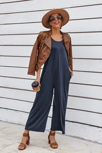 Stylish model wearing a dark grey sleeveless wide-leg jumpsuit with a brown leather jacket