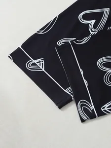 Close-up detail of black pajama pants featuring white heart prints and elegant piping