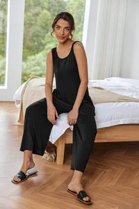 Elegant black sleeveless wide-leg jumpsuit worn by a model in a cozy bedroom setting