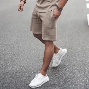 Close-up of men's beige casual shorts with drawstring waist on a model outdoors