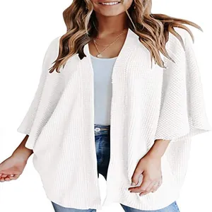 Détail d'un cardigan blanc en maille gaufrée avec des manches chauve-souris pour femmes
