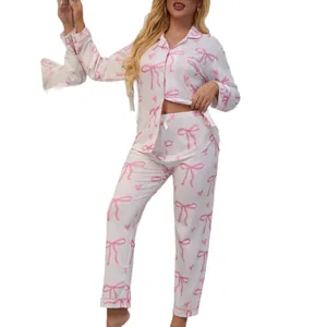 Women's two-piece long-sleeved pajama set featuring pink bow and heart patterns on white fabric