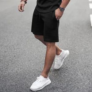 Men's athletic black shorts and t-shirt set shown in a realistic outdoor lifestyle setting