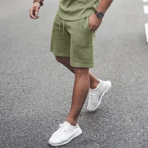 Walking view of men's olive green sports shorts and t-shirt set on asphalt road