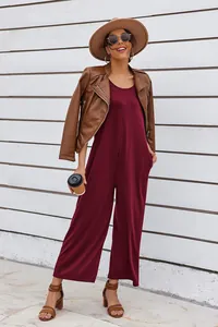 Full-length view of a burgundy sleeveless wide-leg jumpsuit styled with a brown jacket