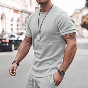 Detail view of men's casual grey t-shirt and shorts set on a model outdoors.