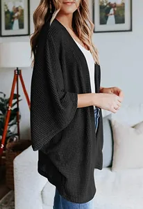 Vue de côté d'un cardigan noir en maille gaufrette avec manches trois-quarts sur un modèle