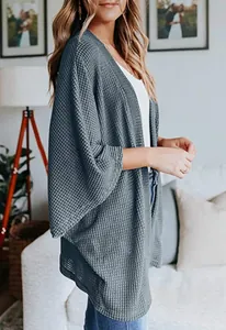 Gilet gris en maille gaufrée avec manches 3/4 larges et détails de texture douce.
