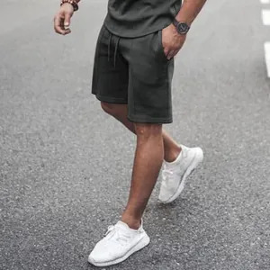 Detailed view of men's grey athletic shorts with drawstring waist on an outdoor model