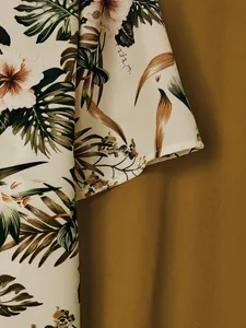 Close-up detail of tropical palm leaf and hibiscus floral print on short sleeve shirt fabric