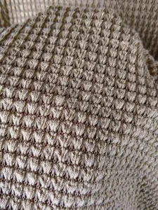 Vue macro détaillée montrant le motif tricoté texturé d'un cardigan d'automne beige
