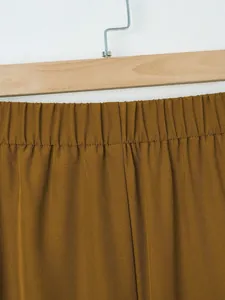 Detail of elastic waistband on casual solid brown trousers with high-quality stitching.
