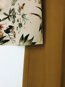 Close-up detail of casual floral print short sleeve top paired with mustard yellow pants