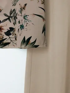 Macro detail showing the floral printed top and solid beige trousers fabric texture.