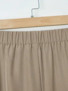 Macro view of the elasticated waistband detail on solid brown casual wide-leg trousers.