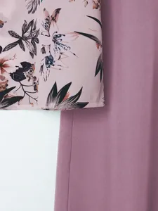 Close-up detail of the elegant floral print top and matching purple trousers set.