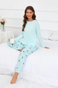 Femme portant un pyjama bleu clair avec imprimés étoiles et lune assise sur un lit blanc
