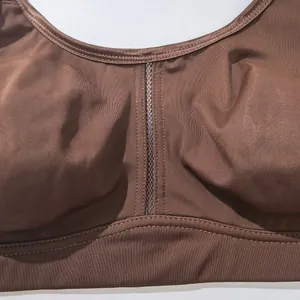 Detail shot of the breathable mesh center and smooth fabric of a brown sports bra