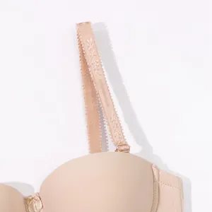 Close-up detail of a seamless nude strapless bra showing decorative lace strap texture.
